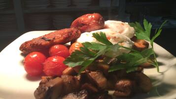 A plate of food with sausages, tomatoes, mushrooms, and a garnish.
