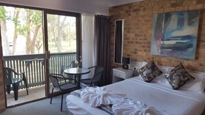 Une chambre d’hôtel avec un lit, un bureau, une chaise, une table et un tableau au mur.