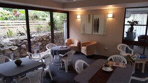 Un coin repas avec un mur en pierre, une petite vue sur le jardin et une table avec des chaises.