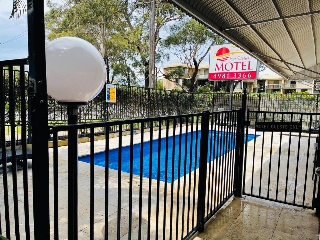 A gated entrance to a motel with a pool area visible beyond the fence.