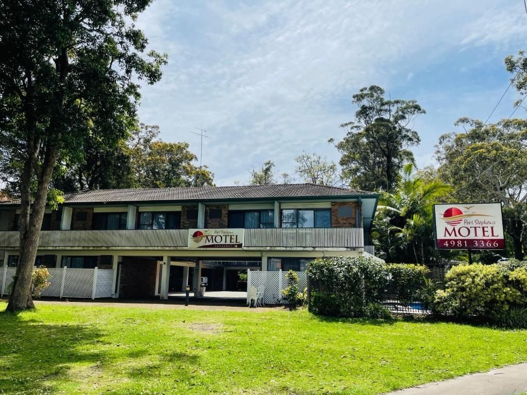 Un motel de dos pisos con techo plano y un cartel.