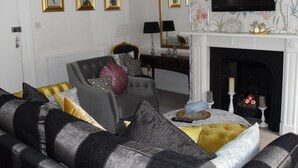 A living room with a fireplace, a television mounted above it, and three framed pictures on the wall. - Jessop House (Tewkesbury)