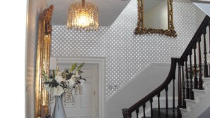 A staircase with a wooden handrail and a white door with a floral arrangement. - Jessop House (Tewkesbury)