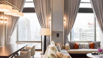 A modern hotel room with a large window, a sofa, a dining table, and a lamp.