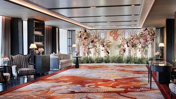 A hotel lobby with a large floral arrangement, a patterned carpet, and a seating area with a sofa and armchairs.