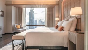 Een moderne hotelkamer met een groot bed, een zithoek en uitzicht op de stadshemel.