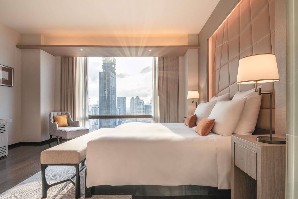 Ein modernes Hotelzimmer mit einem großen Bett, einer Sitzecke und Blick auf die Stadtlandschaft.