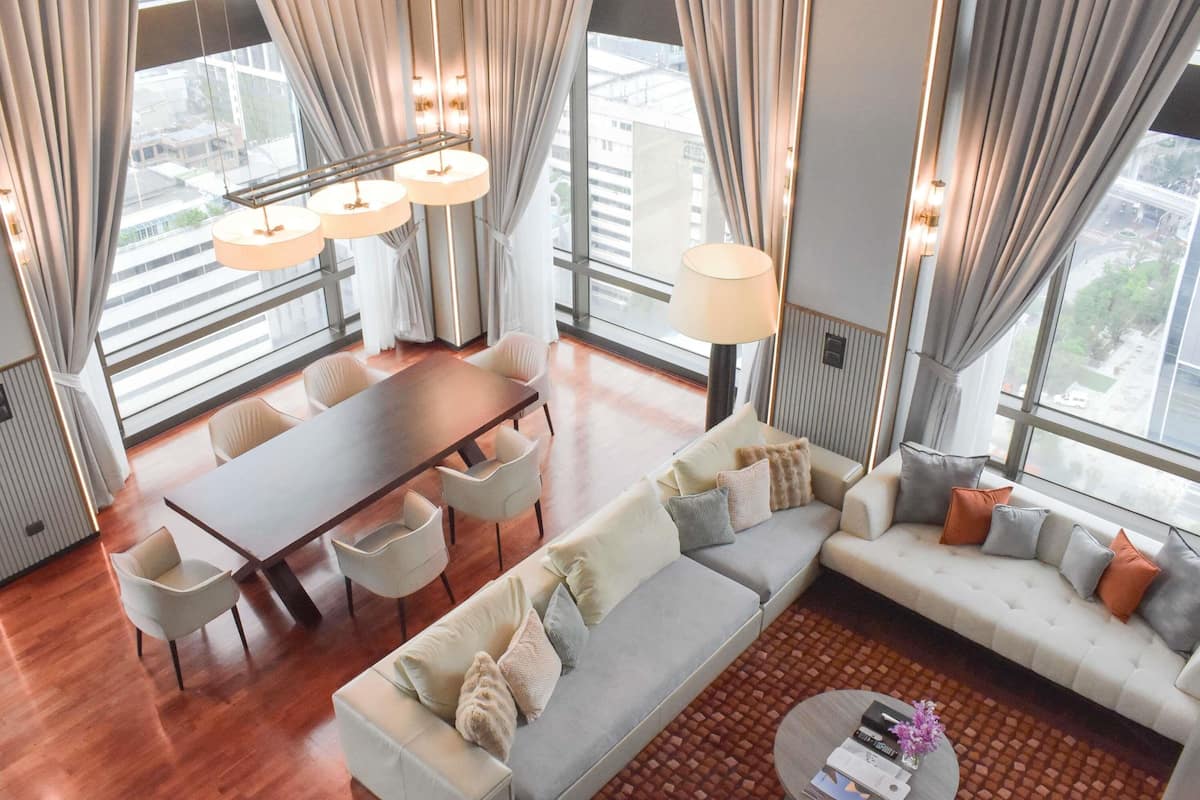 Ein modernes Hotelzimmer mit Essbereich, einer Sitzecke und Blick auf die Stadt.