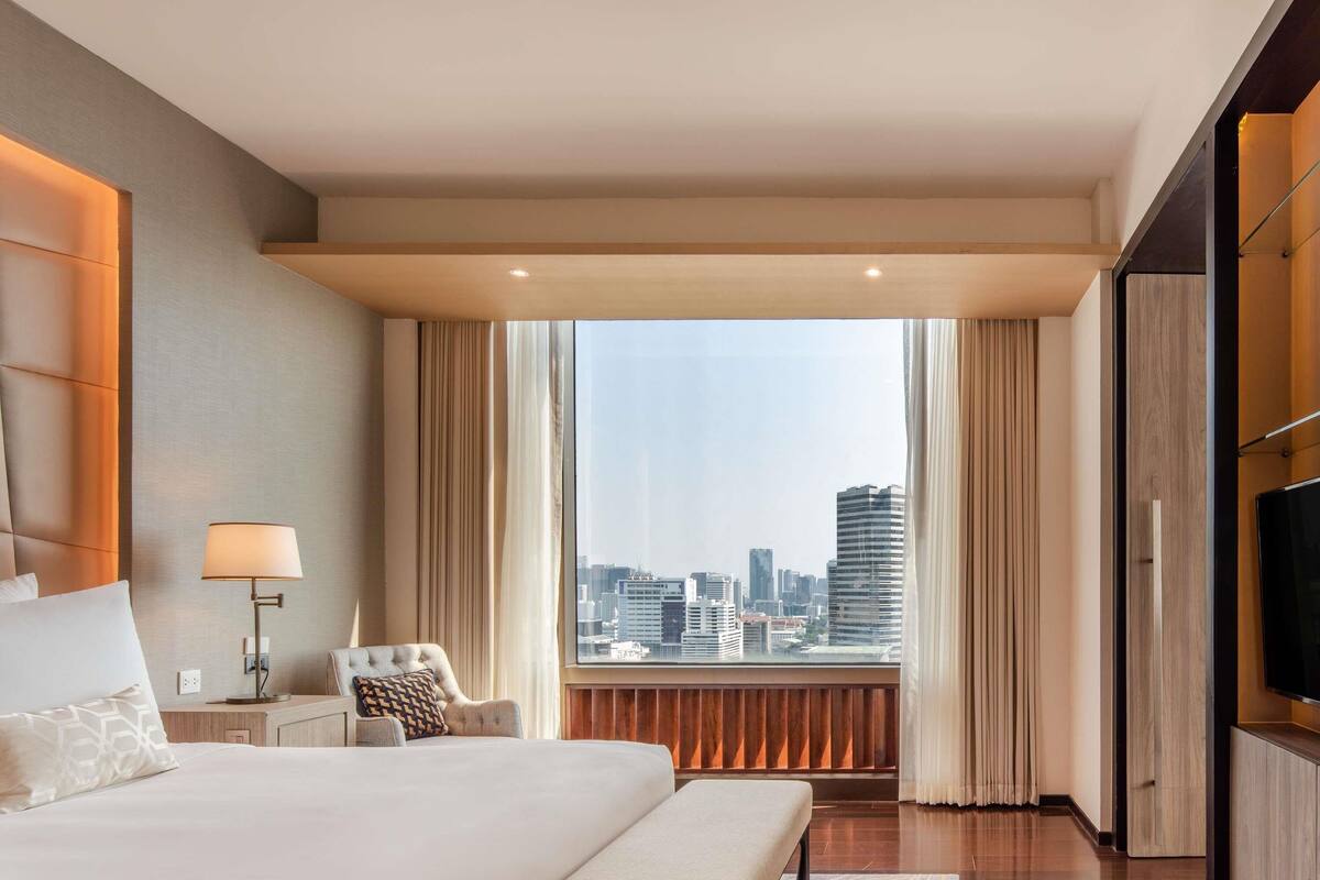 Une chambre d’hôtel moderne équipée d’un grand lit, d’un bureau, d’une chaise et d’une télévision.