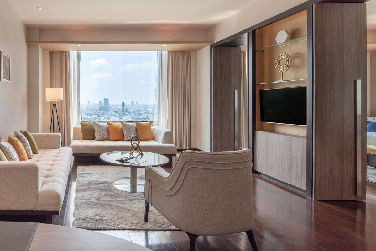 Un salon moderne comprenant un canapé, des fauteuils, une table basse et un téléviseur.