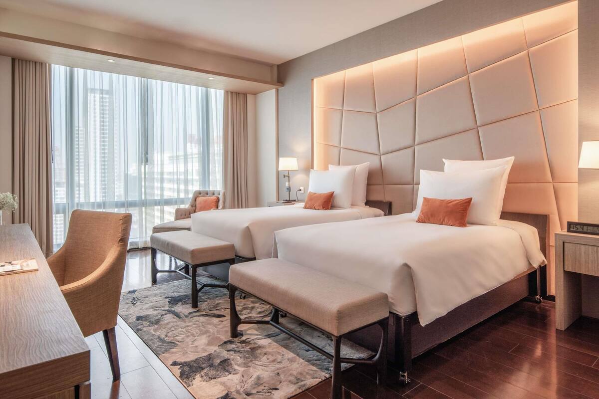 Ein Hotelzimmer mit zwei Betten, einem Schreibtisch und einem Stuhl.