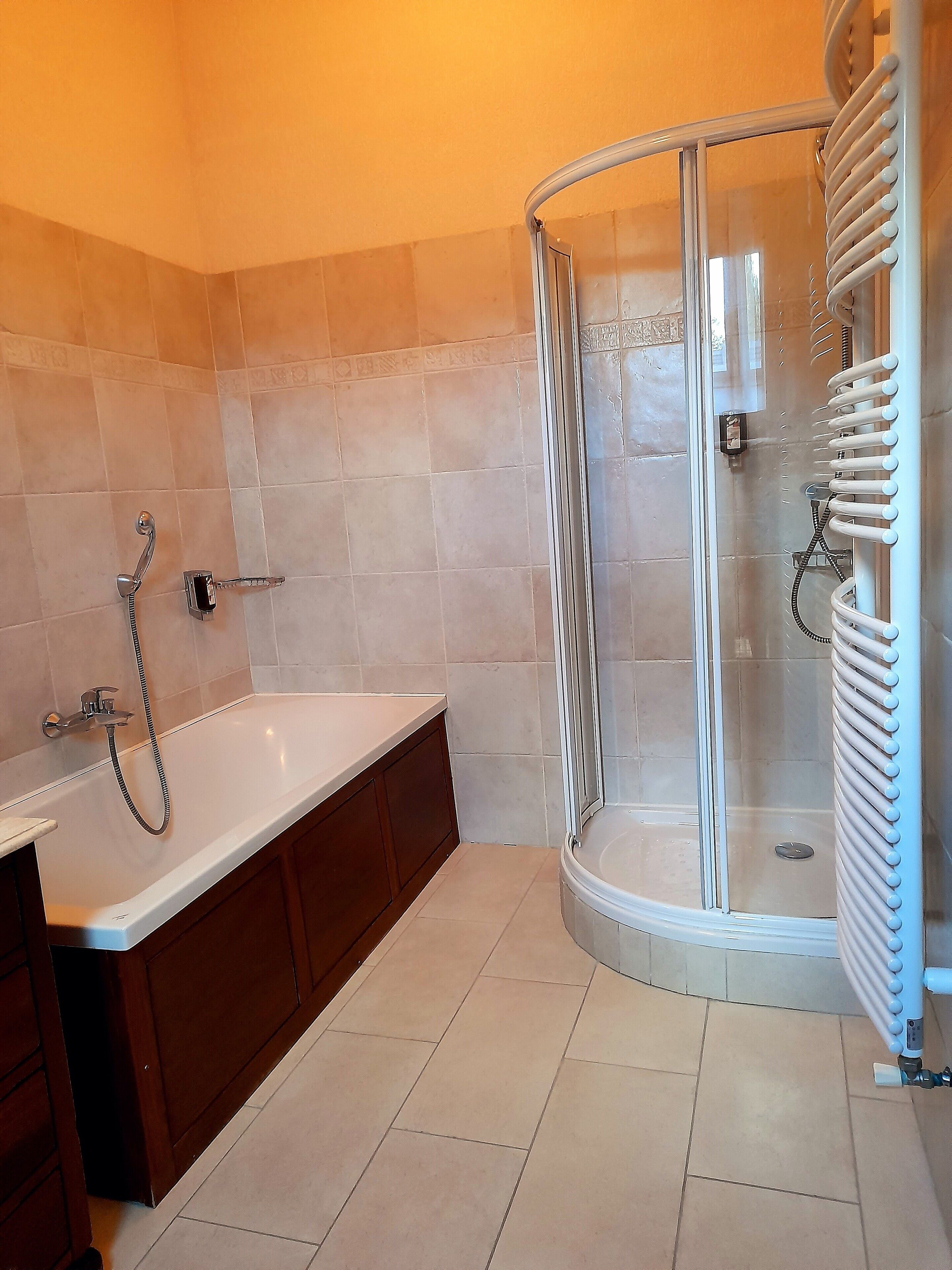 A modern bathroom with a bathtub, shower, and glass-enclosed shower stall.