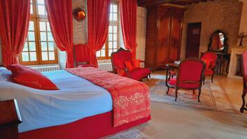 A bedroom with a large bed, red curtains, and a wooden ceiling.