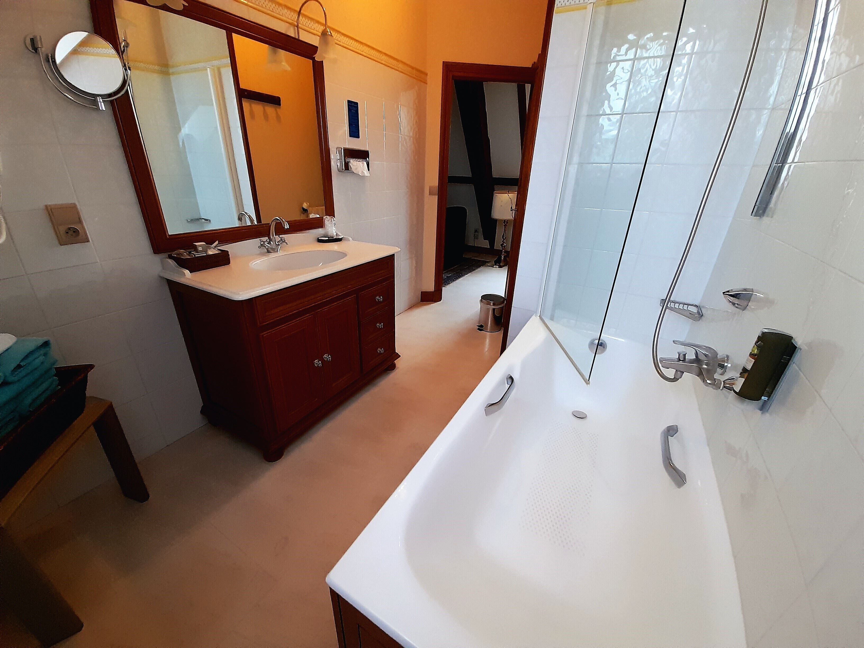 A modern bathroom with a large bathtub, a vanity with a sink, a mirror, and a shower area.