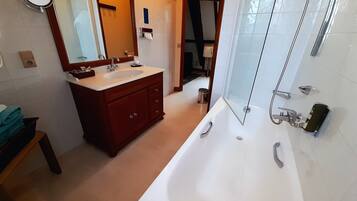 A modern bathroom with a large bathtub, a vanity with a sink, a mirror, and a shower area.