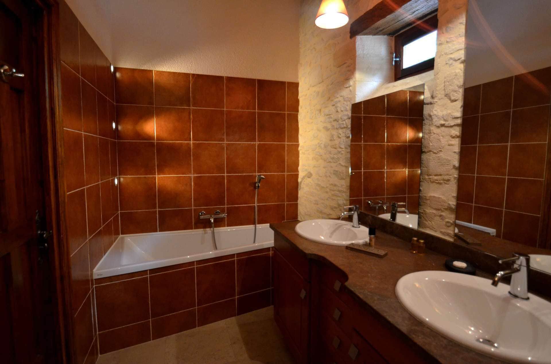 Un baño con bañera, dos lavamanos y una pared de acento de piedra.
