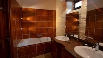 Un baño con bañera, dos lavamanos y una pared de acento de piedra.