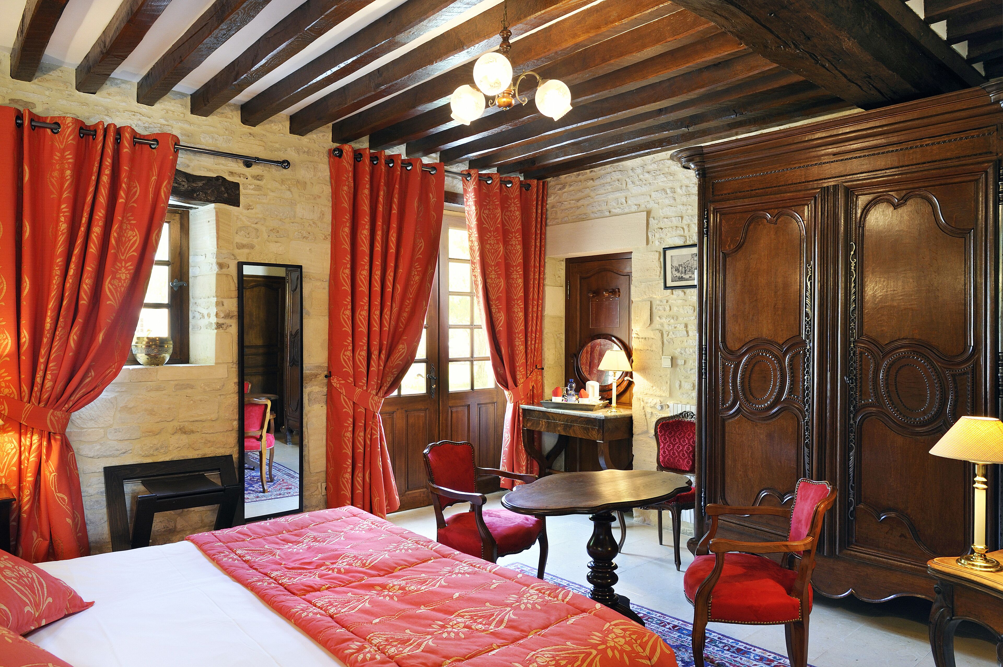 Una stanza con un letto, una scrivania in legno, due sedie e un tavolo.