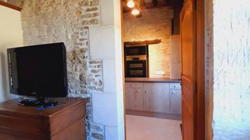 Una cocina rústica con paredes de piedra, vigas de madera y un horno moderno.