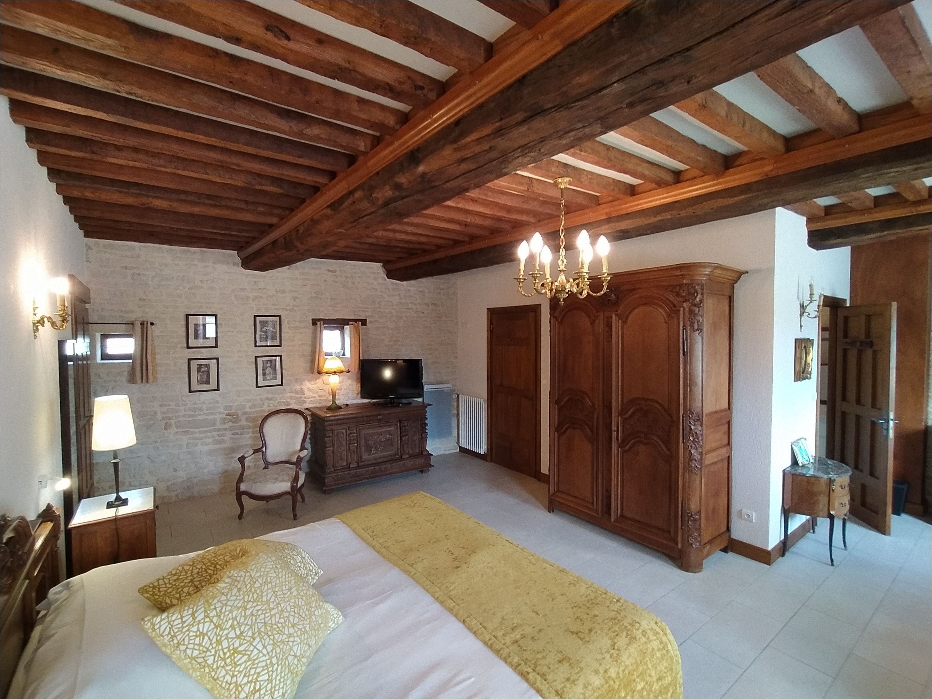 A bedroom with a bed, wooden wardrobe, and a television on a dresser.