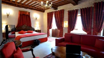 A hotel room with a bed, a sofa, a laptop on a table, and a red carpet.