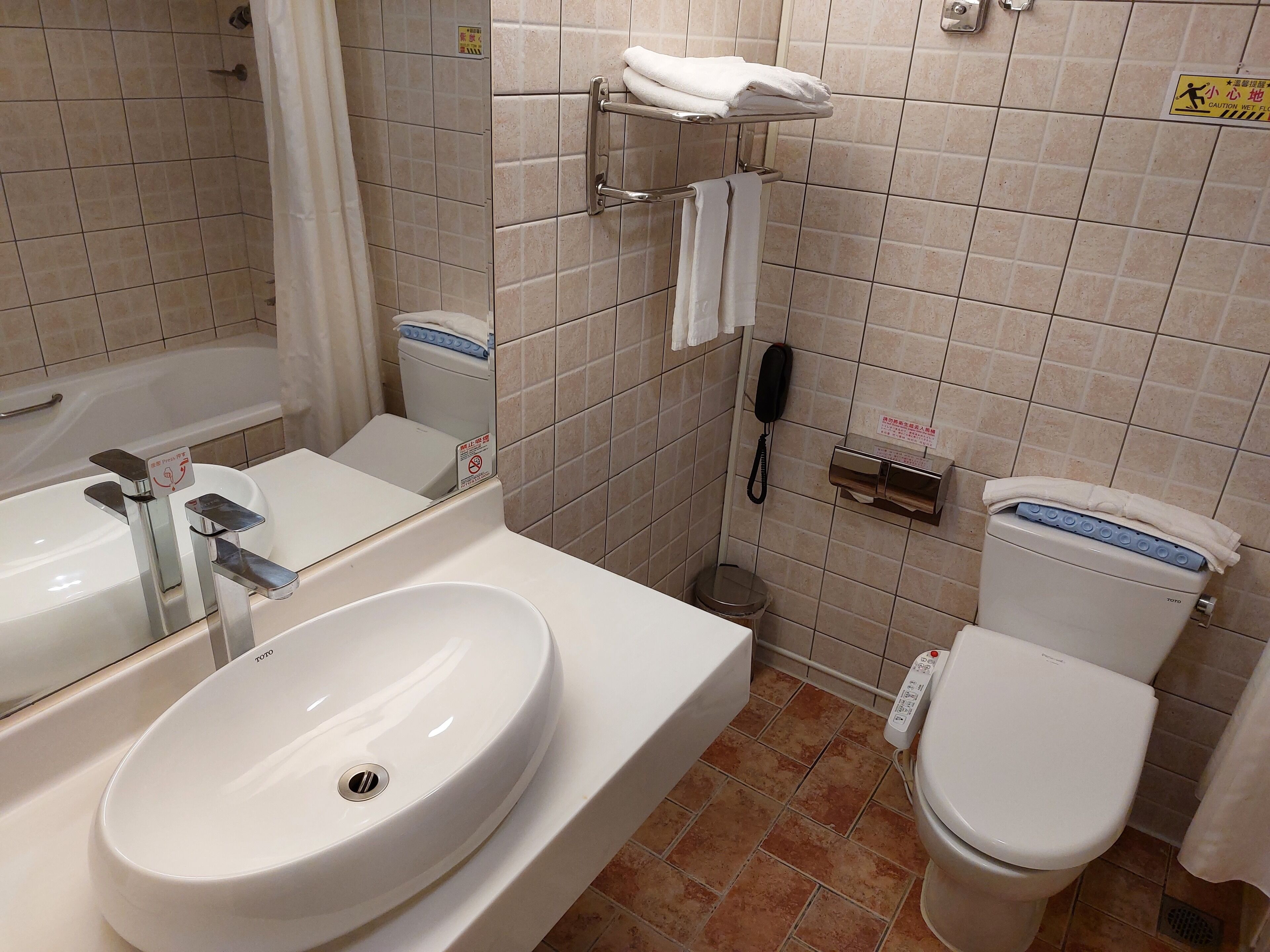 Een badkamer met een wit wastafel, toilet, badkuip en douchegedeelte.