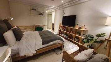 Relax in a serene bedroom with a large bed, flat-screen TV, and natural touches.
