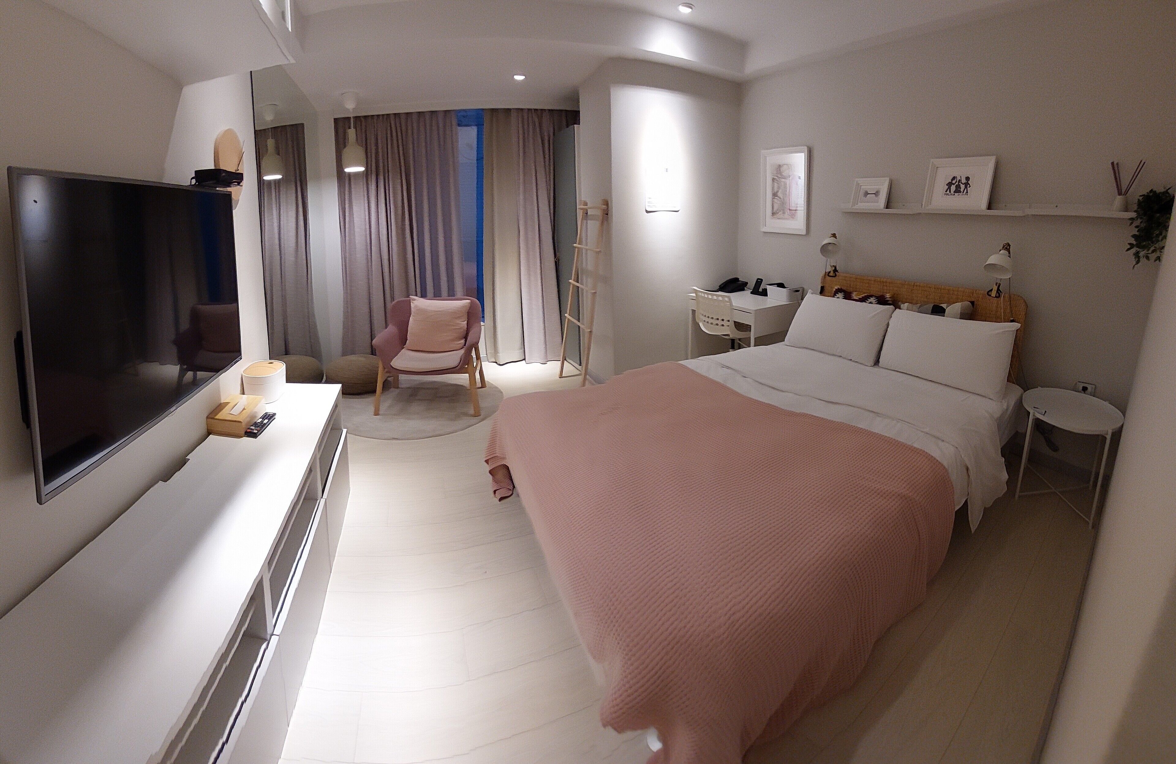 Une chambre d’hôtel avec un grand lit, un bureau, une chaise, une télévision et une armoire.