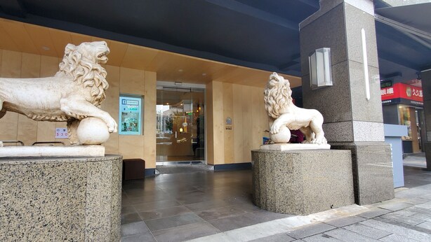A building entrance with two stone lion statues on pedestals.