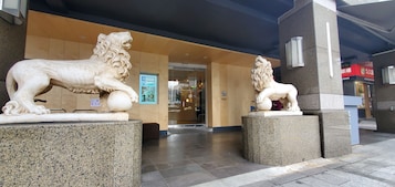A building entrance with two stone lion statues on pedestals.