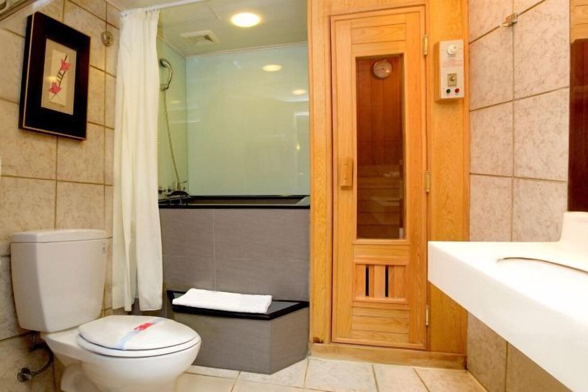 A bathroom with a toilet, a shower, and a sink.