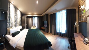 A hotel room with a bed, a desk, a chair, a TV, and a window with curtains.