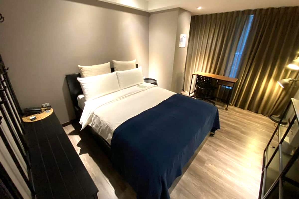 A hotel room with a bed, a desk, and a chair.