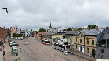 A cobblestone street lined with buildings, a bus, and parked cars.