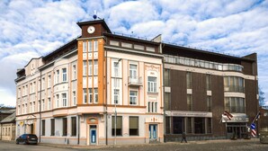 A multi-story building with a clock tower, a restaurant, and a blue door. - Hotel Kolumbs (Liepaja)