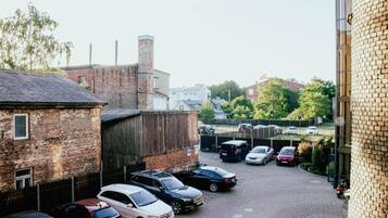 A parking area with multiple cars parked, a brick building, and a fence.