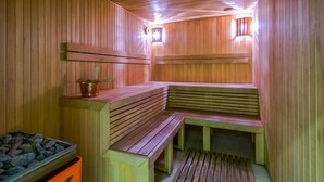 A sauna with wooden benches and a stone basin. - Hotel Kolumbs (Liepaja)