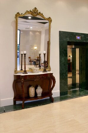 A grand mirror with an ornate frame, a console table with decorative vases, and a marble floor.