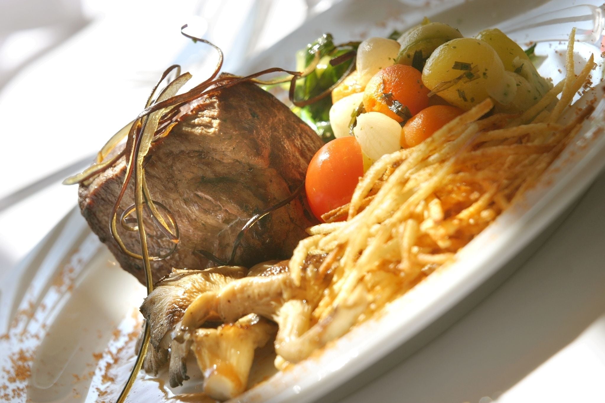 A plate with a roasted meat, vegetables, and a side of noodles.