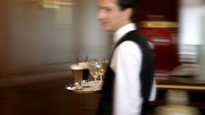 A waiter carrying a tray with glasses and a beverage. - Volos Palace (Volos)