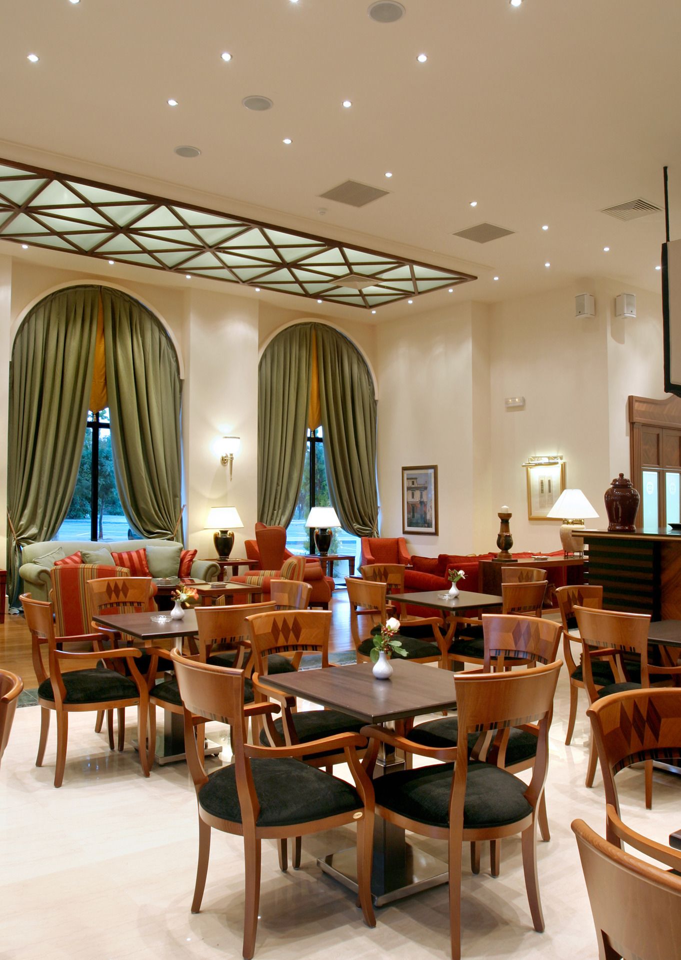 A hotel lobby with a central seating area, multiple tables, and chairs.