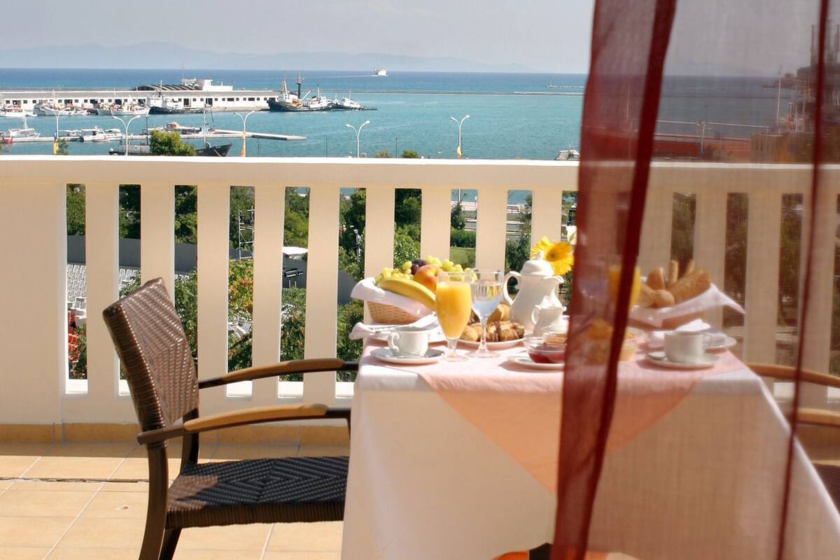 Mesa posta para o café da manhã com vista para o mar e barcos.
