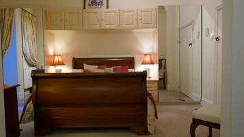 Un dormitorio con una cama de madera, dos lámparas de noche, una mesita de noche, una silla y un armario.