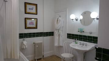 A bathroom with a bathtub, a white sink, a mirror, and framed pictures on the wall.