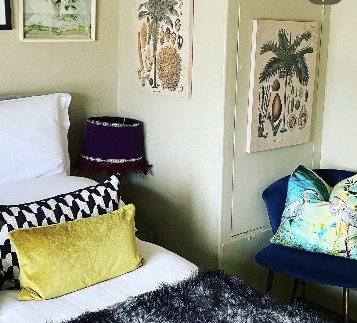 A bedroom with a bed, a chair, and wall art.