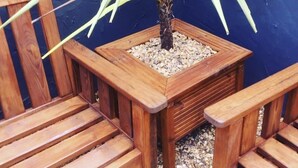 A wooden planter box with a potted plant against a blue wall. - Maison Claire (Chester)