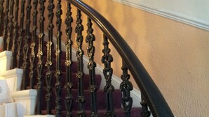 A staircase with ornate black balusters and a handrail, leading to a landing with a white wall and three framed pictures. - Mackenzie Guest House (Edinburgh)
