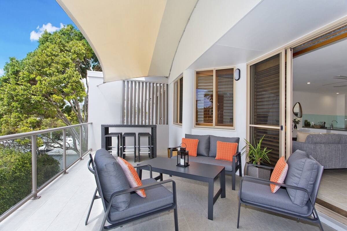 A balcony with a table and chairs, a sofa, and a potted plant.