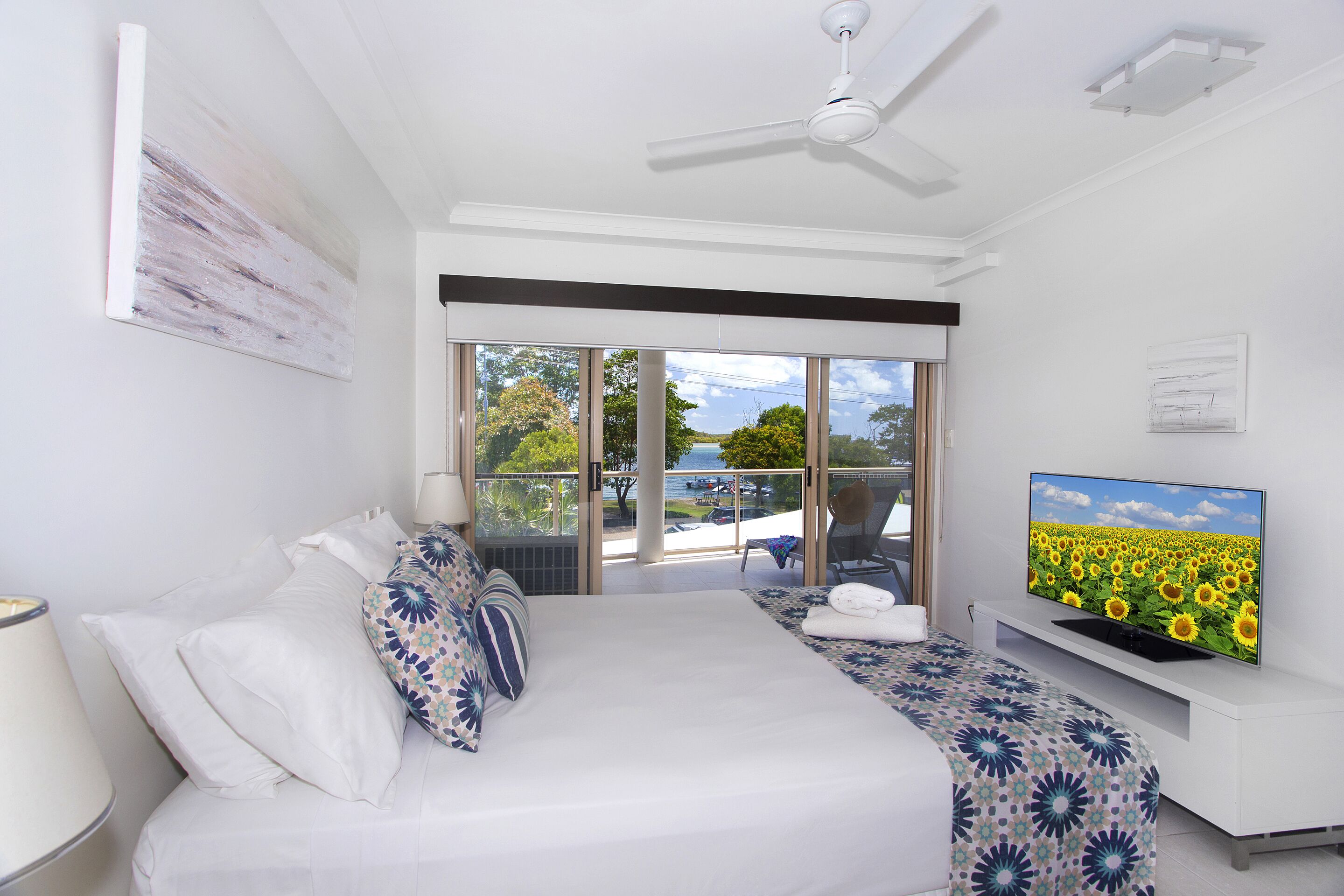 A hotel room with a bed, a TV, a balcony, and a view of the sea.