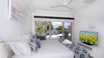 A hotel room with a bed, a TV, a balcony, and a view of the sea.